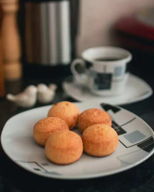 Xícara de café com pães de queijo num pires