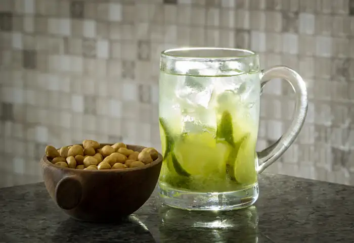 Caipirinha de limão numa caneca com amendoim ao lado