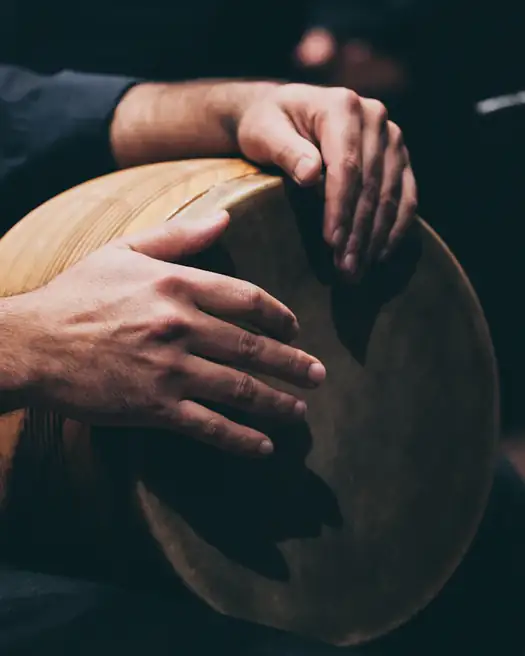Mãos tocando pandeiro numa roda de samba